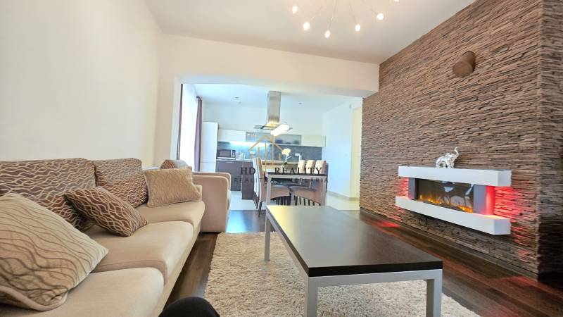Living room in a 3-room apartment with a wooden decor floor, decorative wall, and fireplace.