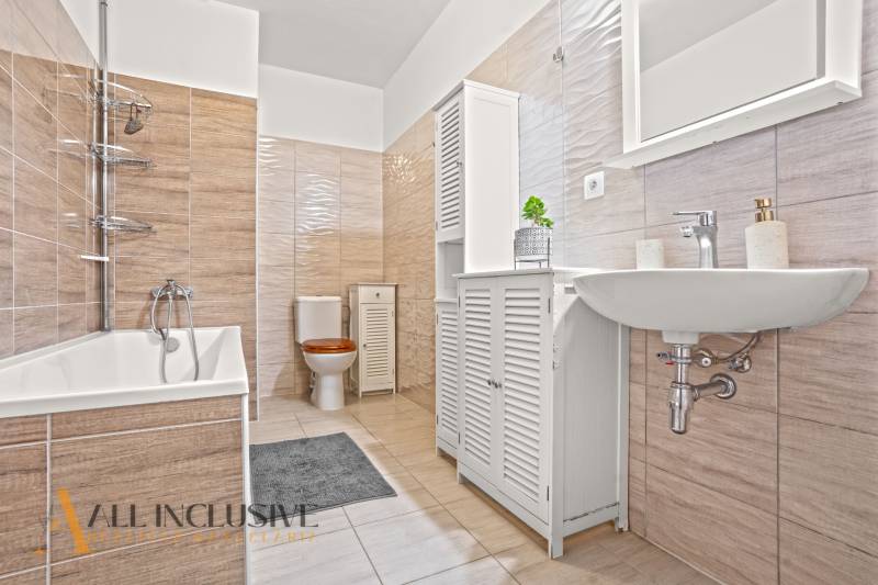 A bathroom with a bathtub and tiles in a 3-room apartment.