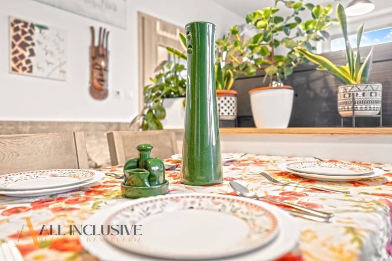 Dining table in a 3-room apartment with a floral tablecloth and decorations.