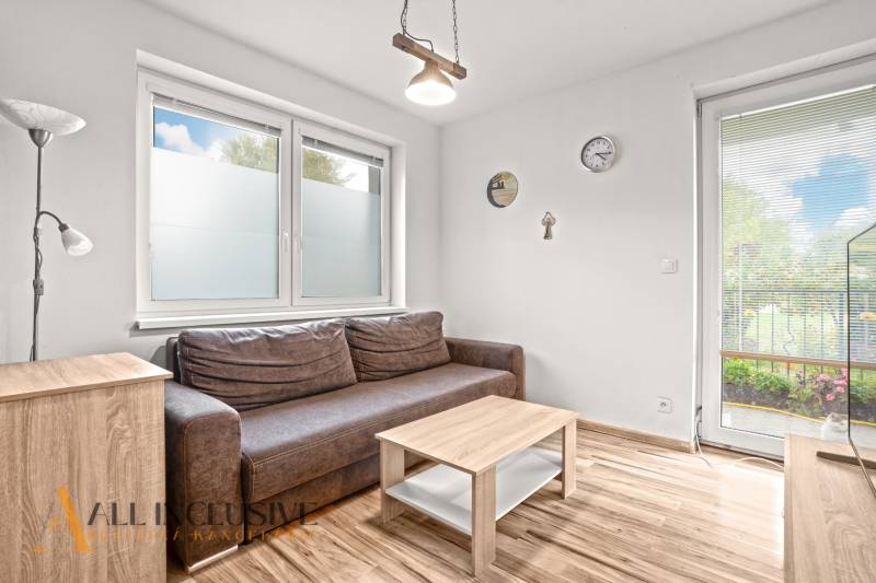 Living room in a 3-room apartment with a brown sofa and a wooden decor floor.