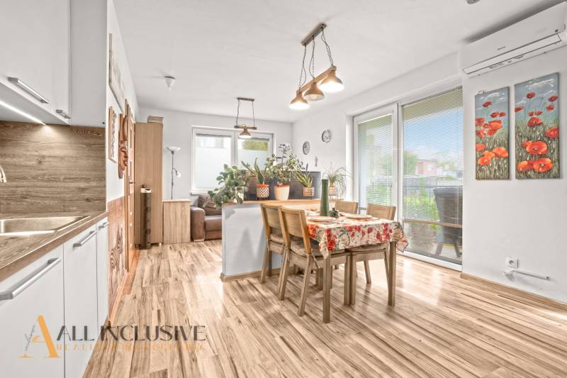Dining room in a 3-room apartment with a wood-patterned floor and plenty of plants.