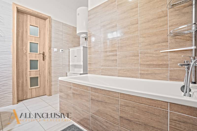 Bathroom in a 3-room apartment with a bathtub, beige tiles, and wooden doors.
