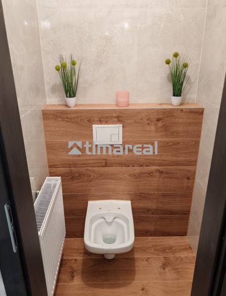 A toilet with a floor and wall with wood decor in a 3-room apartment.