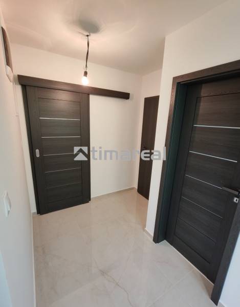 A hallway in a 3-room apartment with dark sliding doors and a light floor.