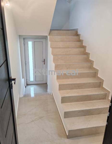 A hallway with a staircase and white walls in a 3-room apartment.