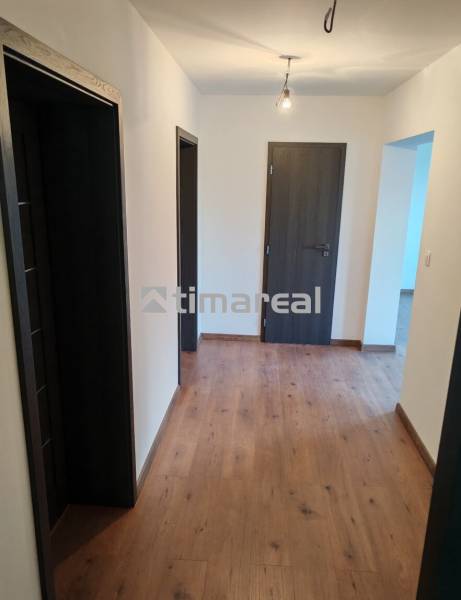 The interior of a three-room apartment with a wood-patterned floor and neutral walls.