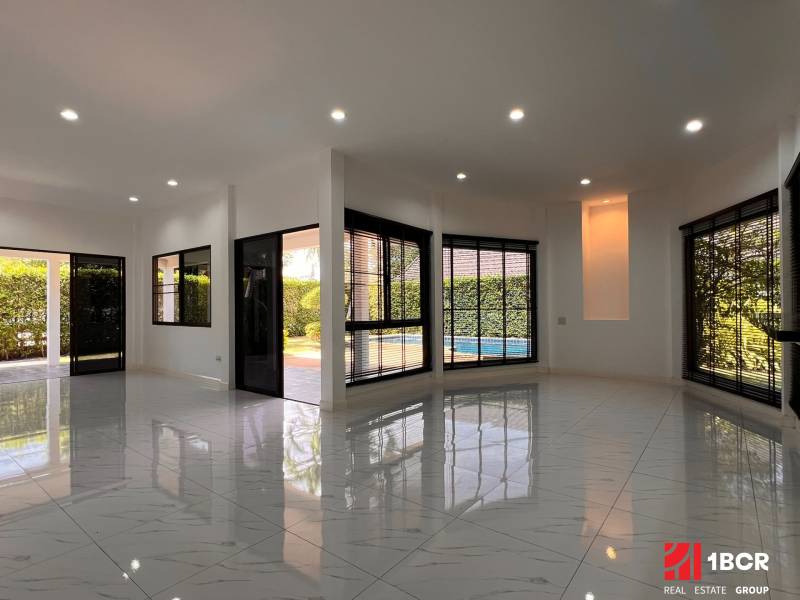 The interior of the villa with white floors and large windows overlooking the garden.