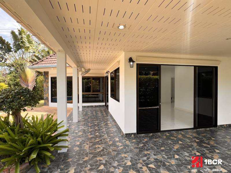 Pattaya villa with a terrace, glass doors, plants, and mosaic paving in the garden.