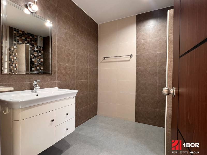 A bathroom in a villa with a sink, mirror, and tile cladding.