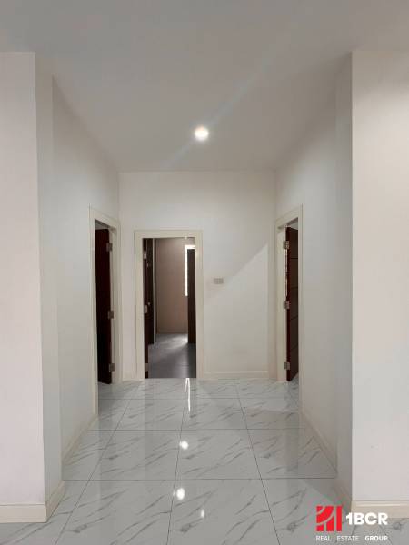 A white hallway in a villa with a marble-like floor and three doors.