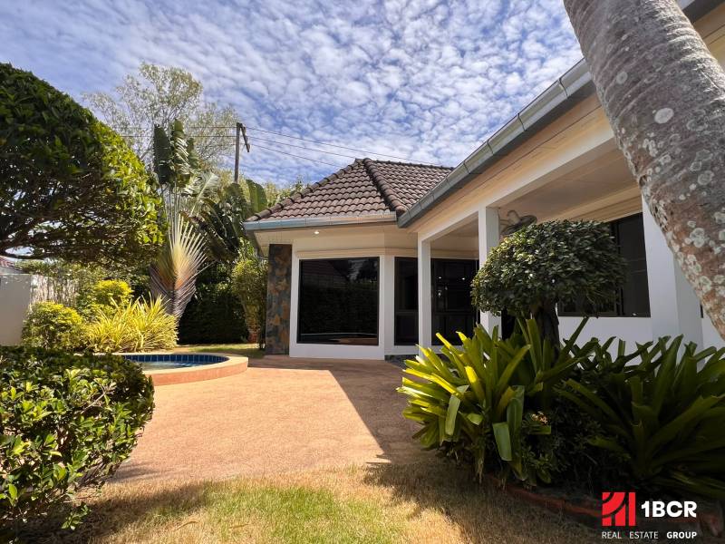 A villa in Pattaya surrounded by a landscaped garden with a paved terrace.