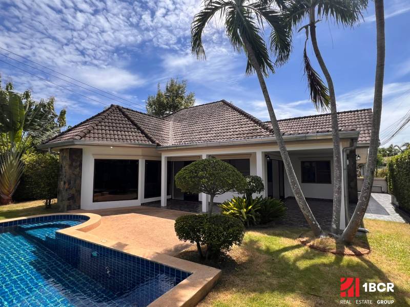 A villa in Pattaya with a pool surrounded by palm trees and greenery.