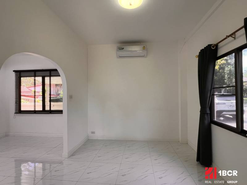 The interior of a villa with a white floor and an arched passage in the wall.