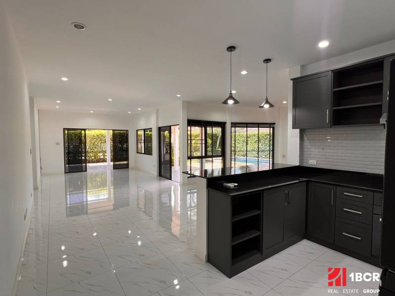 A kitchen in a villa with white walls, tiles, and dark furniture.