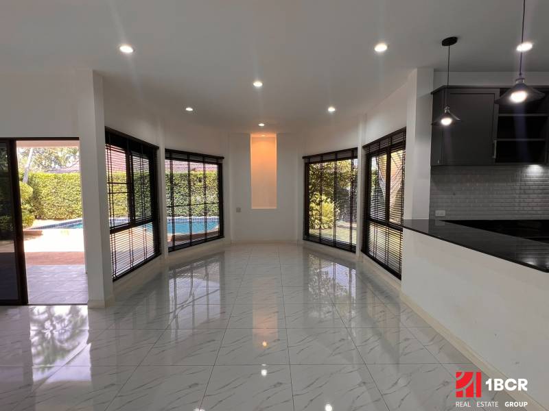 Interior of a villa with a garden view, large windows, and tiled flooring.