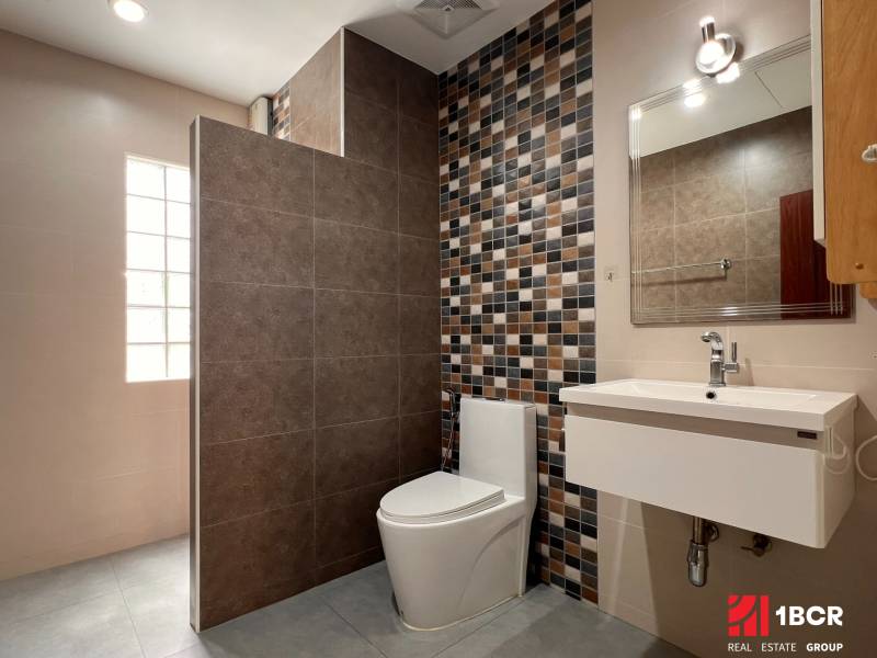 A bathroom in a villa with ceramic tiles and a modern mirror above the sink.