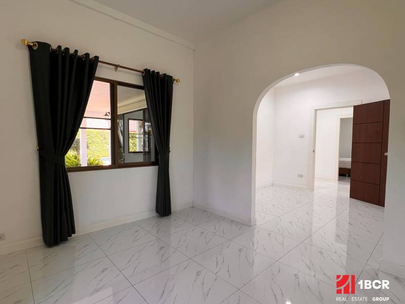 The interior of a villa with a tiled floor, arched doors, and curtains on the window.