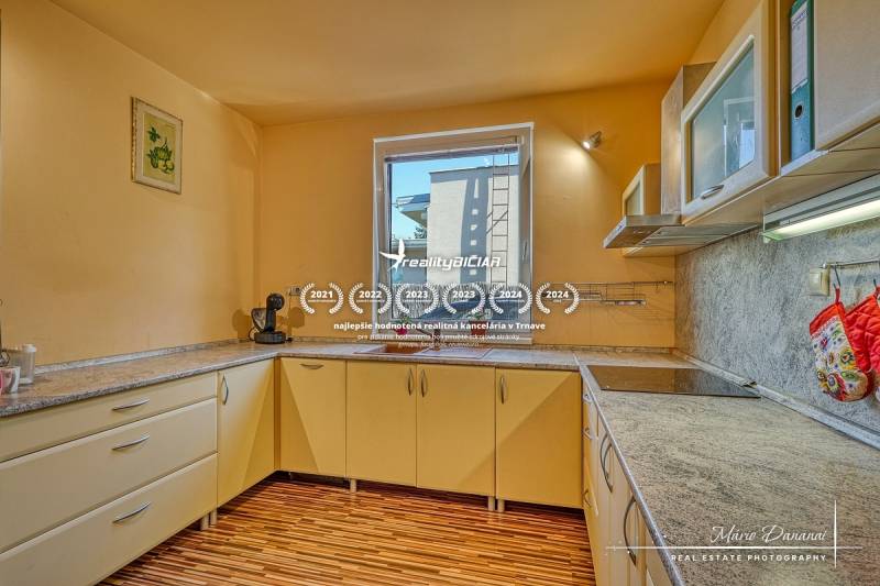 A kitchen in a family house with a window and a floor with a wooden decor.
