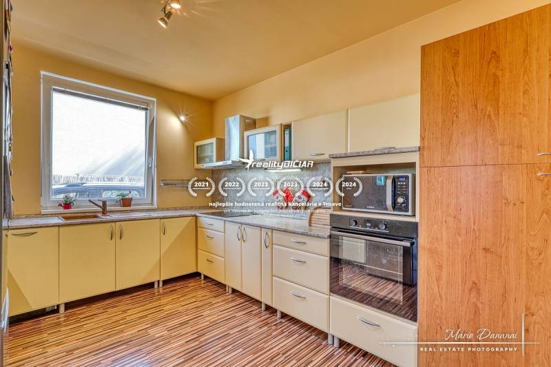 A kitchen in a family house with a wooden decor floor, light kitchen cabinets, built-in appliances.