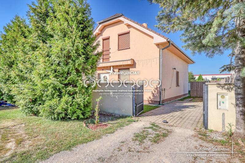 A family house on Cífer Street in Cífer surrounded by trees and green grass.