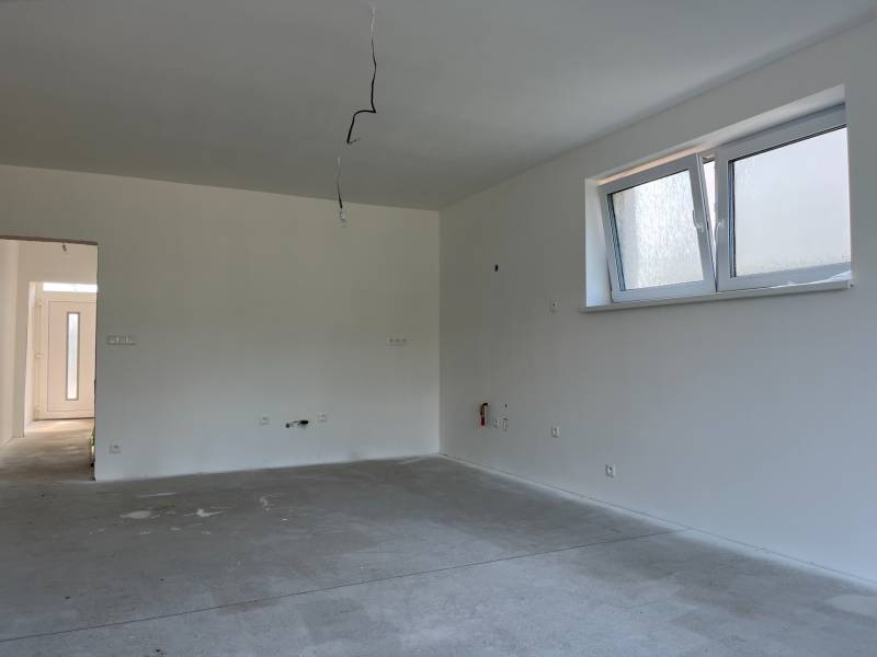 An empty room in a family house with white walls and windows.