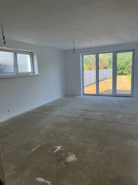 Empty room in a family house with a concrete floor and a large window to the garden.
