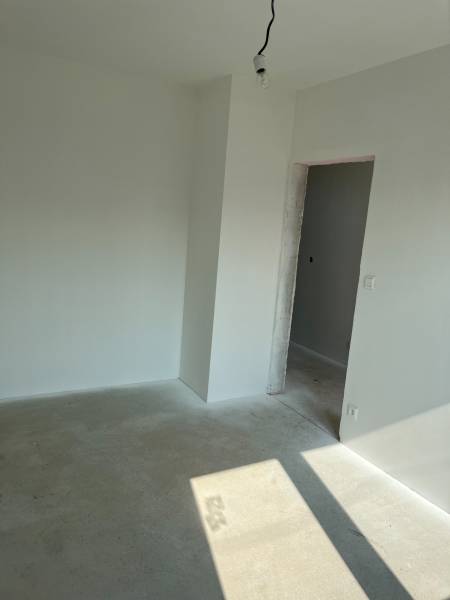 Empty room with white walls and ceiling, concrete floor, preparation in a family house.
