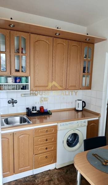Kitchen unit with wood decor, built-in oven and washing machine in a studio apartment.