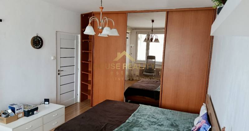 Bedroom with a mirrored wardrobe, bed, and furnishings in a studio apartment.