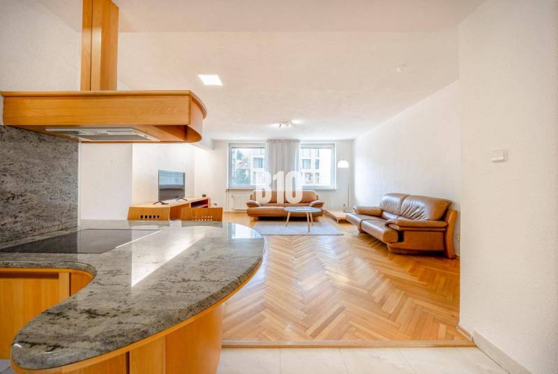 Living room in a three-room apartment with a wooden decor floor and leather furniture.