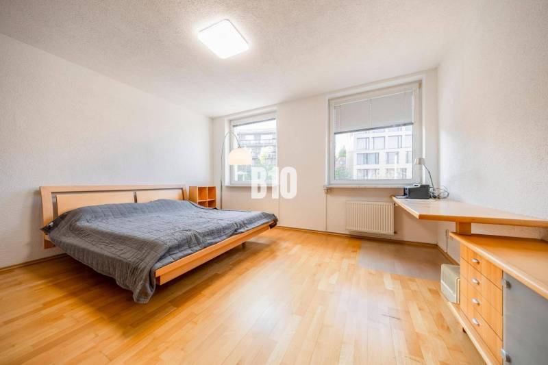 A bedroom in a 3-room apartment with a wooden decor floor and a large bed.