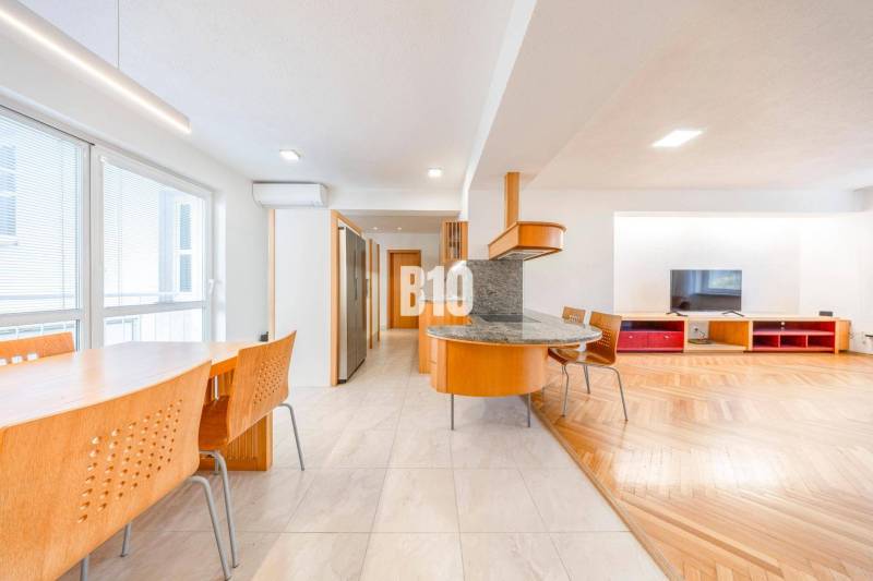 A bright kitchen of a 3-room apartment with a wooden decor floor and a dining table.