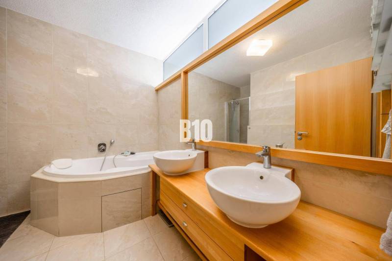 A bathroom with a corner bathtub and two sinks in a 3-room apartment with a wooden decor.