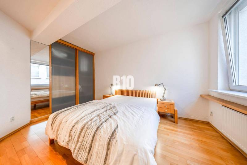 Bedroom in a 3-room apartment with a bed, wardrobe, nightstands, and a floor with a wooden decor.