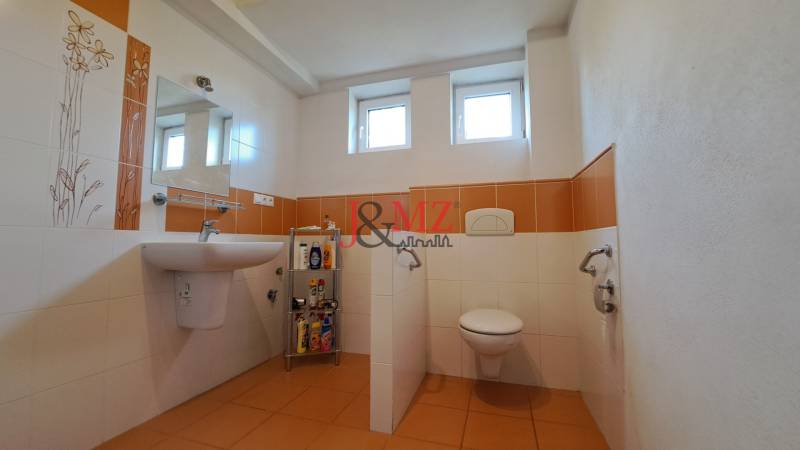 A bathroom in a family house with orange and white tiles and sanitary ware.