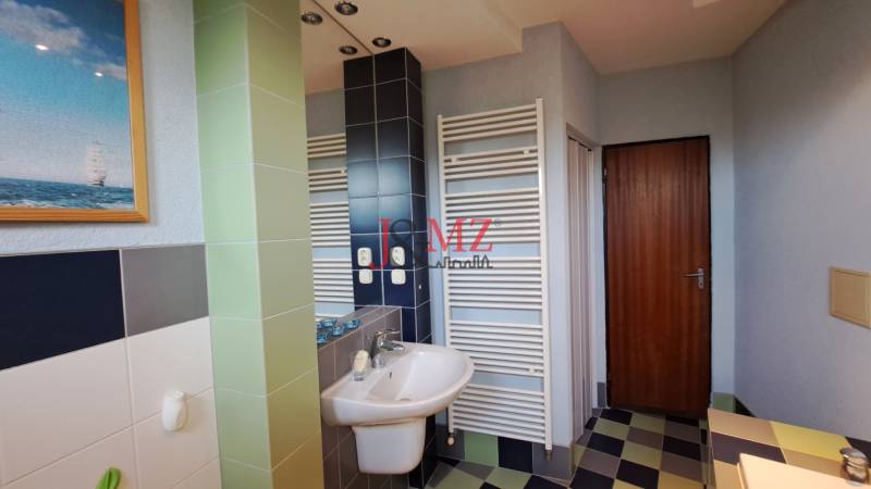 Bathroom in a family house with a sink, shower, and a picture of a sailboat.