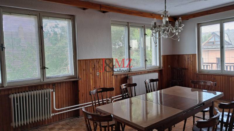 Dining in a family house with wooden paneling, table, and chairs.