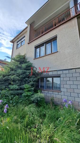 A family house in Hronské Kosihy with a landscaped front garden and a brick facade cladding.