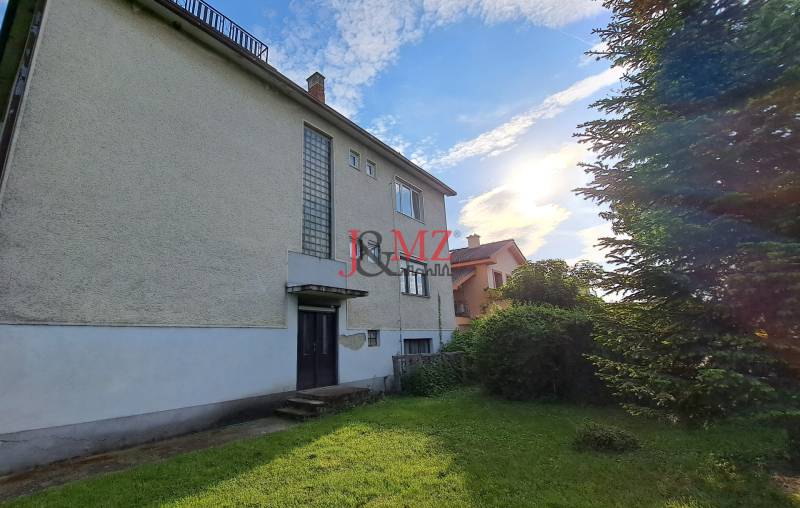 A family house in Hronské Kosihy with a garden, trees, and a clear sky.