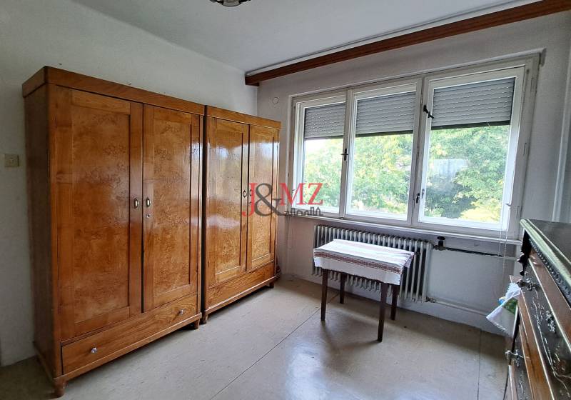 A room in a family house with a large wardrobe, a table, and a window.