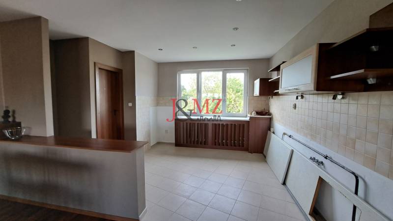 A kitchen in a family house with light walls and wooden cabinets.