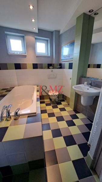 A bathroom in a family house with a tiled floor and a bathtub, spacious and bright.