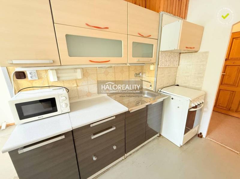 A kitchen in a 2-room apartment with a kitchenette, stove, microwave, and storage space.