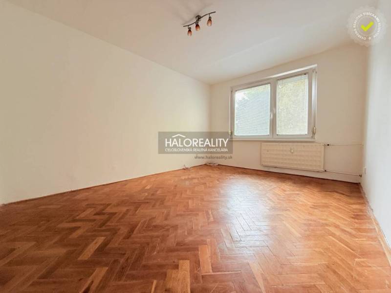 A room in a 2-bedroom apartment with a wood-decor floor and a large window.