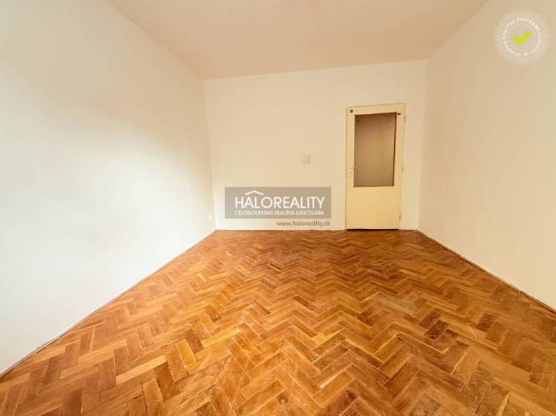 A room in a 2-room apartment with a wood-decorated floor and light-colored walls.
