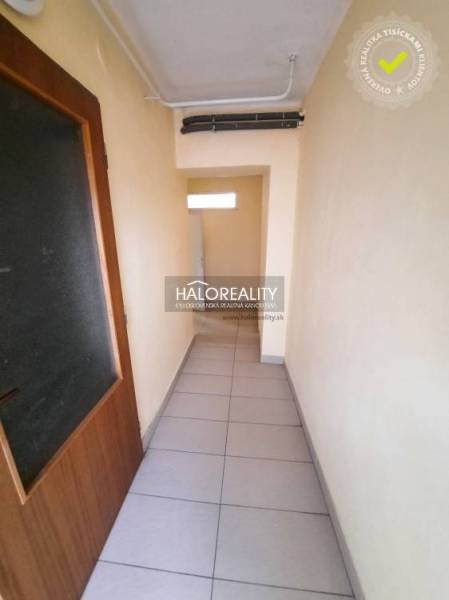 A narrow hallway with tiles and wooden doors in an office.