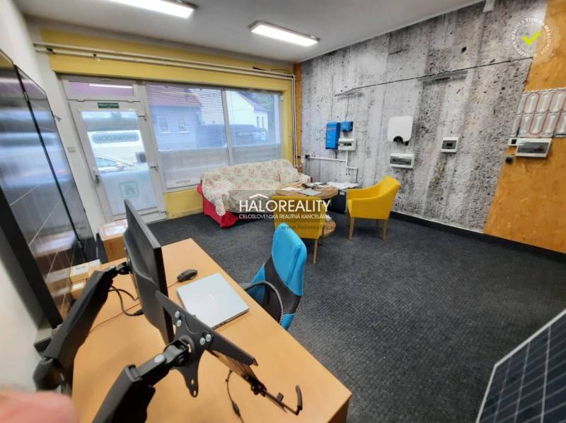 Office with carpet, computers, sofa, and colorful chairs.