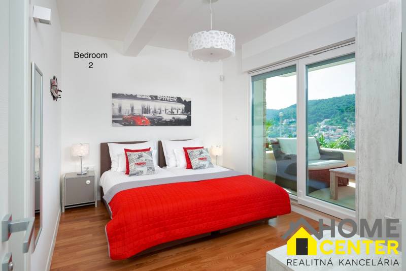 Bedroom in a villa with wood-patterned flooring, a bed, and a balcony with a view.