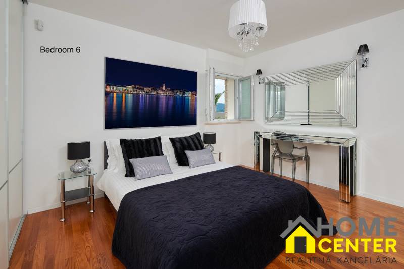 Bedroom in a villa with wood-decor flooring, a mirror, and a stylish bed.