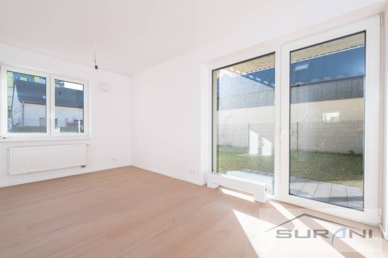 A bright room and a wooden decor floor in a 2-room apartment, with a view of the garden.